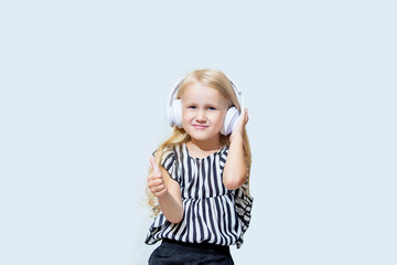 Little child girl beautiful fashion and happy in the white earphones listening to music on an isolated background