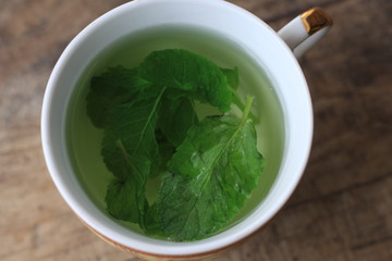 leaves of green mint and a cup of tea