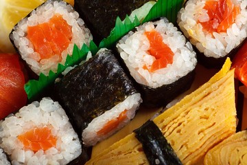 Black and red sushi sashimi set on a wooden bridge on a brown wooden table. With tune, prawn,...