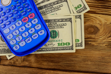 Calculator and american dollars banknotes on wooden table. Top view