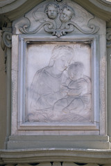 Fototapeta na wymiar Virgin Mary with baby Jesus, relief on the house facade in Florence, Italy