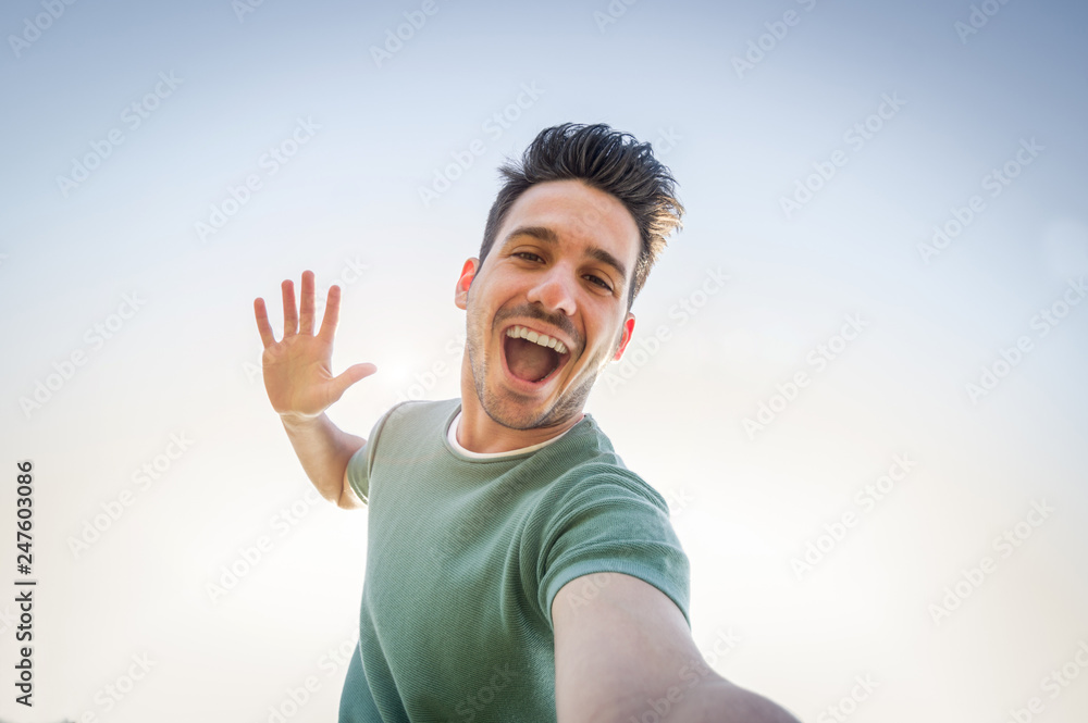 Wall mural man taking a selfie on a blue sky background