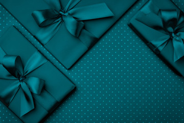 Gift box with green ribbon bow dark turquoise background top view. Holiday concept, birthday gift, New year or Christmas gift box Xmas holiday. Congratulations greeting card with copy space. Flat Lay