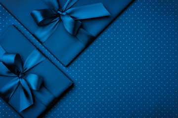 Gift box with ribbon bow on dark blue background top view. Holiday concept, birthday gift, New year...