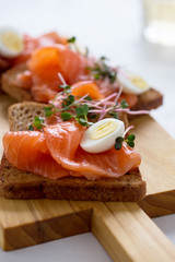 Toasts with smoked salmon garnished with quail egg and radish sprouts