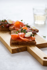 Toasts with smoked salmon garnished with quail egg and radish sprouts