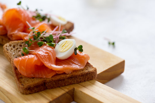 Toasts with smoked salmon garnished with quail egg and radish sprouts