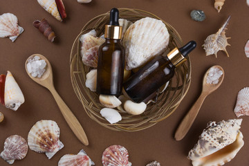 Fototapeta na wymiar top view cosmetic oil bottles and sea salt on brown background with shells