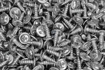 a large number of galvanized self-tightening screws as a background