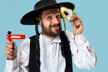 Portrait of a young orthodox Hasdim Jewish man with wooden Grager Ratchet at Jewish festival of Purim at studio. The purim, jewish, festival, holiday, celebration, judaism, pastry, tradition, cookie