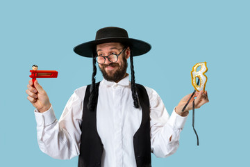 Portrait of a young orthodox Hasdim Jewish man with wooden Grager Ratchet at Jewish festival of Purim at studio. The purim, jewish, festival, holiday, celebration, judaism, pastry, tradition, cookie