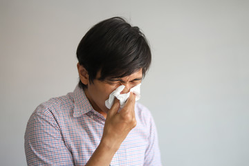 Asian man wipe his nose with tissue looks