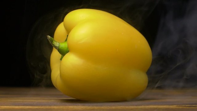 sweet yellow bell pepper or capsicum is on the table in cold, steam from frost in slow motion, cloese up