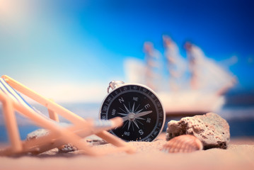 Time to Travel. Idea for tourism with compass and chaise lounge on the sand with corals on the background of the sea and ship.