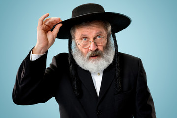Portrait of old senior orthodox Hasdim Jewish man with wooden Grager Ratchet at Jewish festival of...