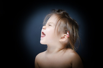 Child showing tongue on dark background. little girl bullying