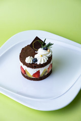 Chocolate cake with whip cream and fruit. Set on green background..