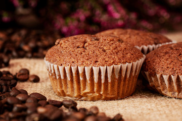 Muffins with coffee beans on a jute bag with a dark background. Detail view.