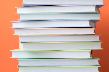 Stack of colorful books on orange background . Education background. Back to school.