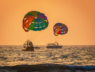 amazing shot at sunset of Parasailing water amusement - flying on a parachute behind a boat on a summer holiday by the sea in the resort Baga beach Goa India India watersports