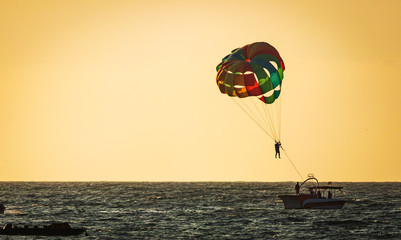 amazing shot at sunset of Parasailing water amusement - flying on a parachute behind a boat on a summer holiday by the sea in the resort Baga beach Goa India India watersports
