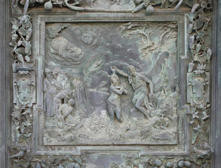 Jesus Christ's Baptism, sculpture work from Giambologna's school, collocated in the left portal panel of the Cathedral St. Mary of the Assumption in Pisa, Italy 