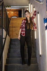 Beautiful and sexy girl posing for a photographer on the black iron stairs with lamps in a cafe.