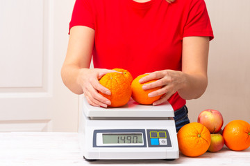 woman weighting fruints on digital weight scales