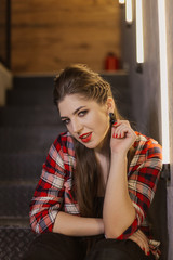Beautiful and sexy girl posing for a photographer on the black iron stairs with lamps in a cafe.