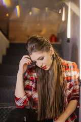 Beautiful and sexy girl posing for a photographer on the black iron stairs with lamps in a cafe.