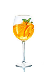 orange cocktail in wine glass with mint on white background