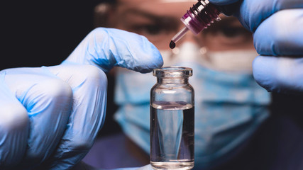 Laboratory worker scientist laboratory assistant tests chemicals for reactions in test tubes,...