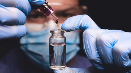Laboratory worker scientist laboratory assistant tests chemicals for reactions in test tubes,...