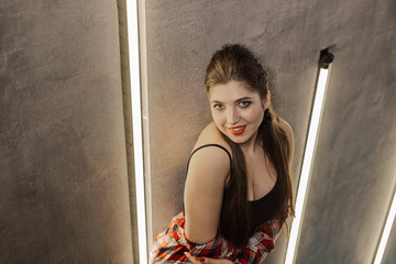 Beautiful and sexy girl posing for a photographer on the black iron stairs with lamps in a cafe.