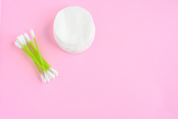 Clean cotton stack of disk for beauty hygiene with selective focus and individual ear sticks with sterile softness applicator on pink neutral background. Ear swabs and face sponges for health