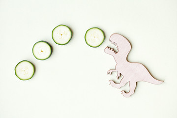 funny strong dinosaur eating tasty zucchini, healthy vegetables for children, funny meal, flat lay