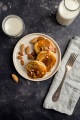 American pancakes with caramel and nuts at black background