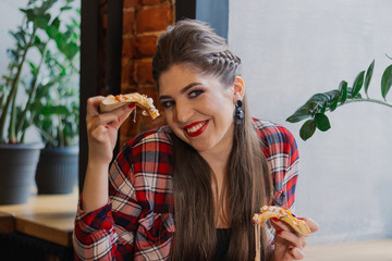 Beautiful and sexy girl sitting at a table with a pizza in a cafe.