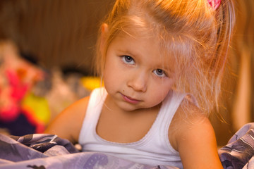 Little girl smiling and playing in bed, evening