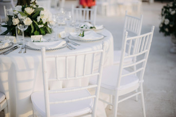 Fototapeta na wymiar Classic white set of wedding dinner table. White bouquets as a centerpiece
