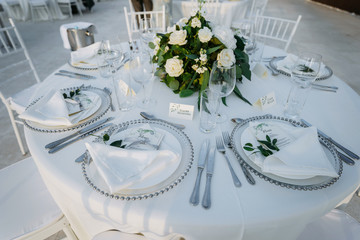 Classic white set of wedding dinner table. White bouquets as a centerpiece