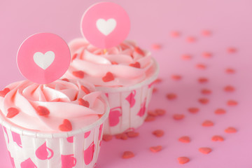Tasty pink pastel butter cream cupcakes on red background, delicious butter cream cupcakes, Valentines cupcakes, hearts for Valentines, Valentines day card concept.