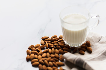 Almond milk in a glass surrounded by organic almonds