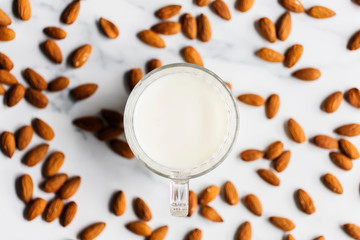 Obraz na płótnie Canvas Almond milk in a glass surrounded by organic almonds