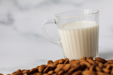 Almond milk in a glass surrounded by organic almonds