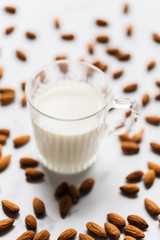 Almond milk in a glass surrounded by organic almonds