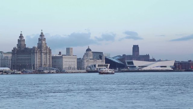 Mersey ferry crosses in front of Liverpool  skyline at dusk
