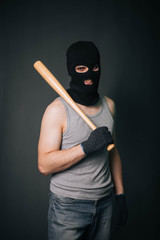 Bandit, the criminal in a black mask and in a gray T-shirt with a painless bat. Robber with a...