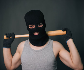 Bandit, the criminal in a black mask and in a gray T-shirt with a painless bat. Robber with a...