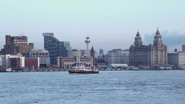 Mersey ferry crosses in front of Liverpool  skyline at dusk